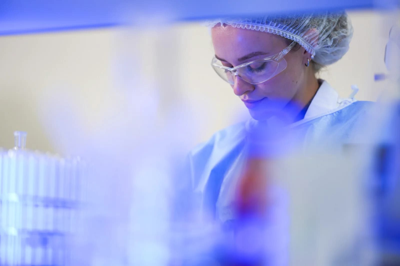Scientist in safety glasses and hairnet working in a lab
